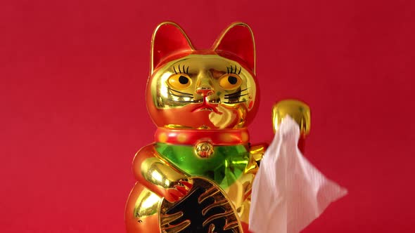 Sitting Maneki-neko cat waving goodbye with tissue