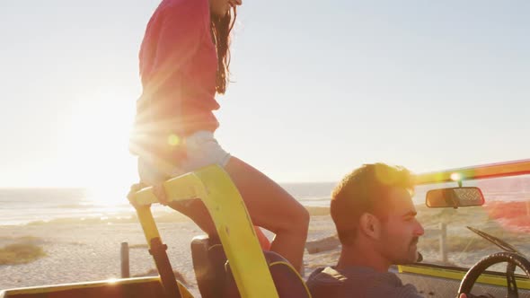 Happy caucasian couple sitting in beach buggy by the sea talking