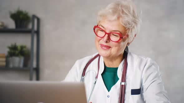 Elderly Woman Doctor Works at the Computer