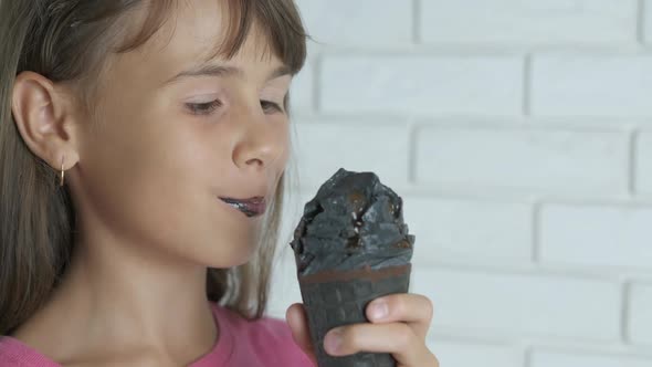 The girl eats black ice cream. 