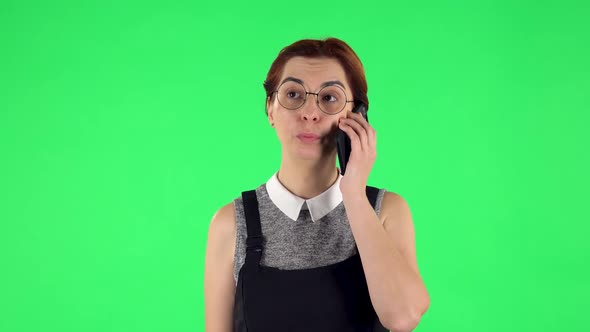 Portrait of Funny Girl in Round Glasses Is Talking for Mobile Phone and Very Shocked. Green Screen