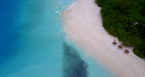 Luxury aerial tourism shot of a white sandy paradise beach and blue sea background 
