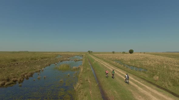 Aerial view tracking cyclists on dirt road, Ibera Wetlands, Corrientes Province, Argentina