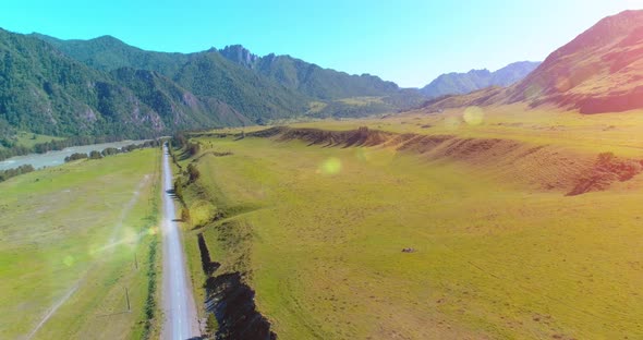 Aerial Rural Mountain Road and Meadow at Sunny Summer Morning. Asphalt Highway and River.