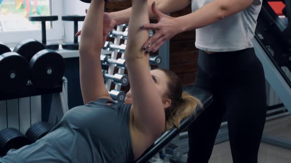 A Personal Trainer Helps His Client to Work Out in the Gym and Do Exercises with Dumbbells Correctly