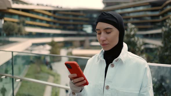 Portrait of Arabian Lady Standing Near Shopping Center and Using Smartphone