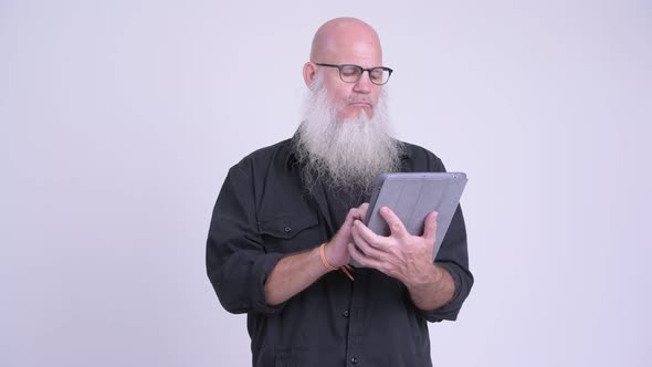 Happy Mature Bald Bearded Man Using Digital Tablet and Getting Good News