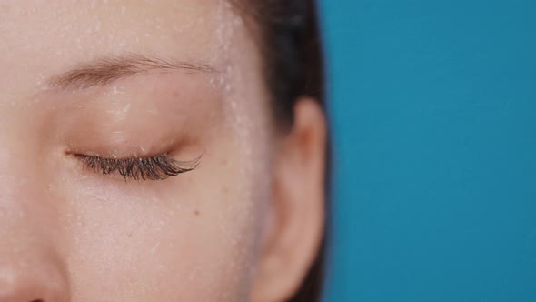 Close-up of Closed Woman Eye with Water Splashes and Drops Isolated on Blue