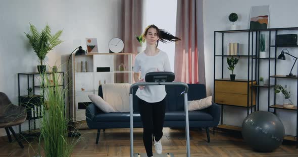 Active Confident Sportive 25-aged Woman Running on Treadmill in Cozy Apartment