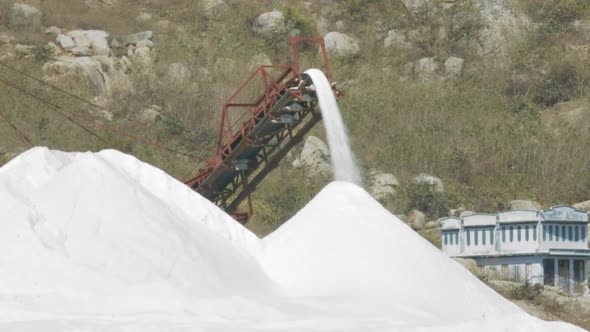 Conveyor Belt Pours Salt To Heap Against Hill