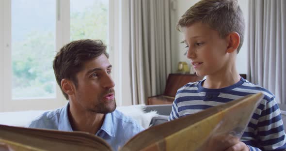 Father and son reading story book at home 4k