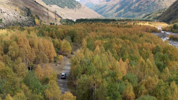 Drone Above Suv Auto Driving on Dirt Road Among Colorful Trees in the Autumn Forest on Mountain