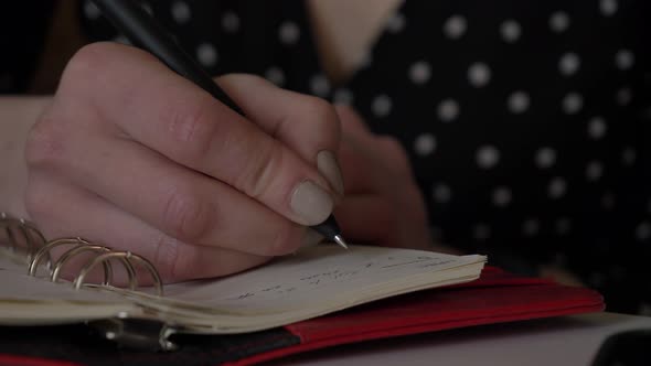 Closeup view as woman writing some notes in a notebook