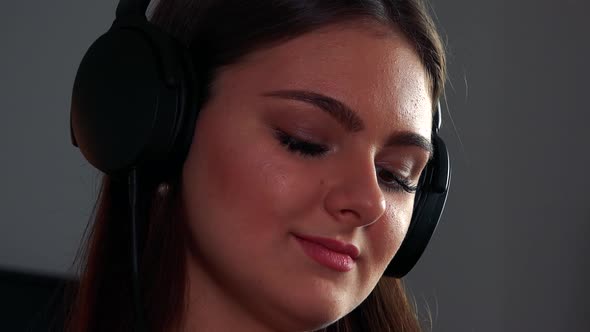 A Young Beautiful Woman Puts on Headphones and Listens To Music with a Smile - Face Closeup