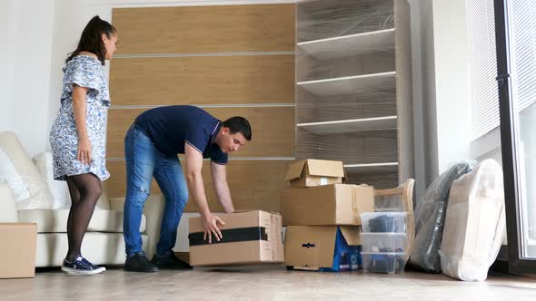 Man and Woman Moving Cardboard Boxes in New Home