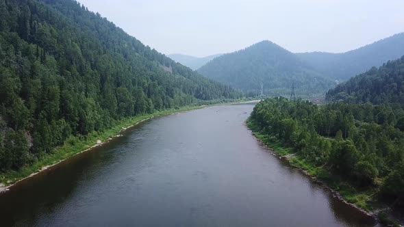 Drone Flies Over River in Mountainous Countryside.