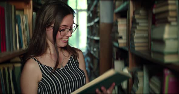 Girl in Glasses and Teeth Braces Rejoices When Reading Book in a Library