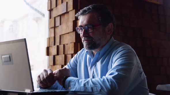 Cheerful Senior Businessman Making Video Conference Online with Client at Remote Workplace