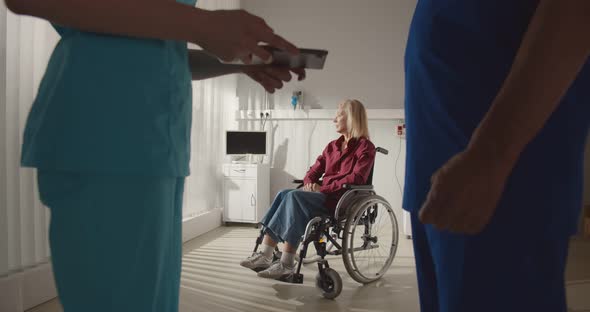 Cropped Shot of Doctors Discussing Treatment of Disabled Woman Sitting in Wheelchair on Background