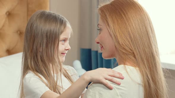 Cute Little Girl Hugging Her Mother with Her Eyes Closed