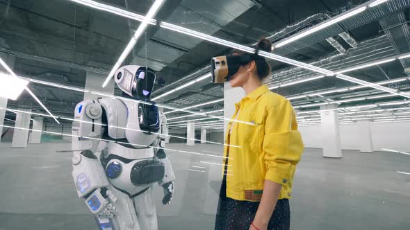 Human-like Robot Is Touching a Hand of a Woman in VR-glasses