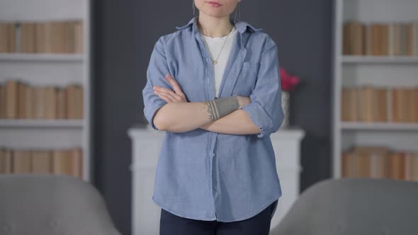 Impatient Young Unrecognizable Woman with Crossed Hands Tapping Finger on Arm Standing Indoors