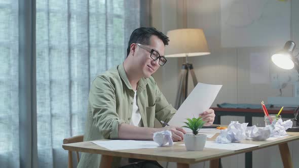 Asian Man Designer Positively Shaking His Head While Looking At The Layout Bond At The Office