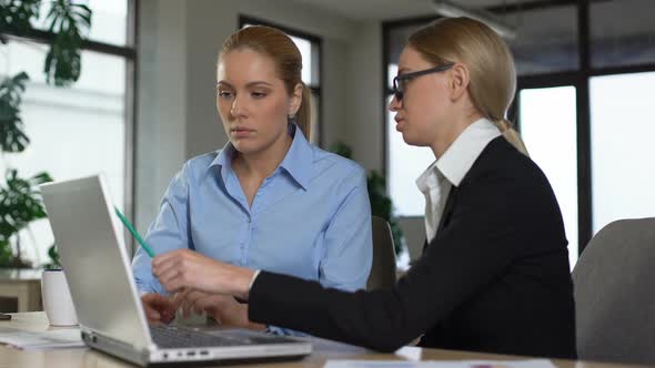 Experienced Manager Teaching Trainee in Office Explaining Project on Laptop