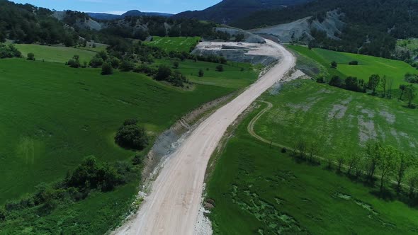 Dirt road in the green valley, road construction.