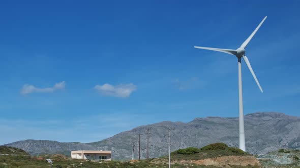 Single Wind Turbine in Hill Landscape on Sunny Day