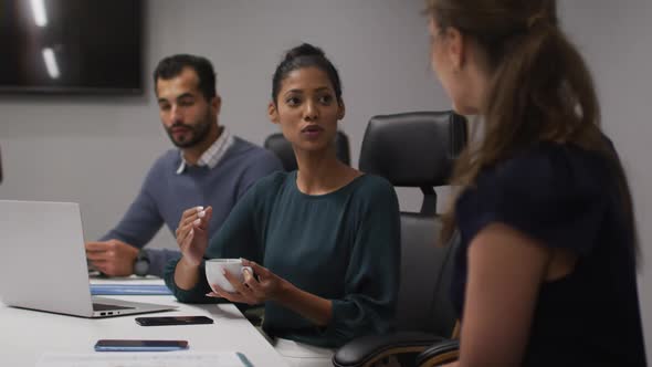 Two diverse female office colleagues talking to each other in meeting room at office