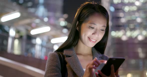 Business woman use of mobile phone in city at night