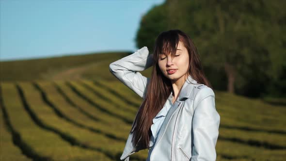 Sensual Brunette Girl Is Touching Long Hair Standing Outdoors in Summer Evening