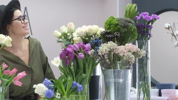 Portrait of happy Beautiful European florist girl in florist shop among flowers