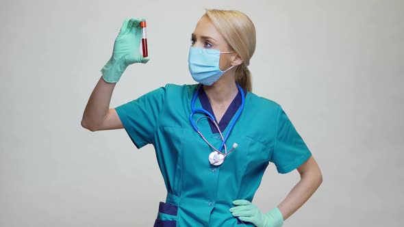 Medical Doctor Nurse Woman Wearing Protective Mask and Latex Gloves - Holding Blood Test Tube