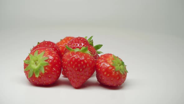 Six Red Strawberries Rotating On The Table With Pure White Background  - Close Up Shot