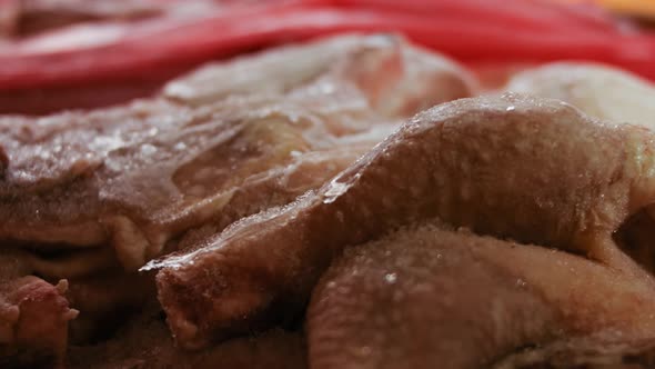 Closeup View of Hands in Gloves Packing Chicken Legs From a Box Into Individual Plastic Bags