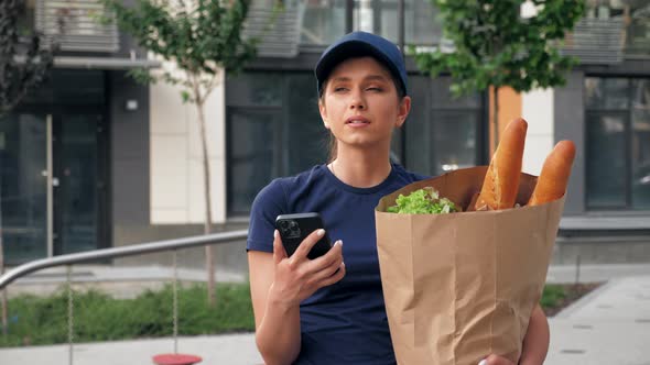 Food Delivery Woman Courier Uses Smartphone Holds Paper Bag Looking Address