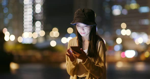 Woman use of mobile phone in city at night