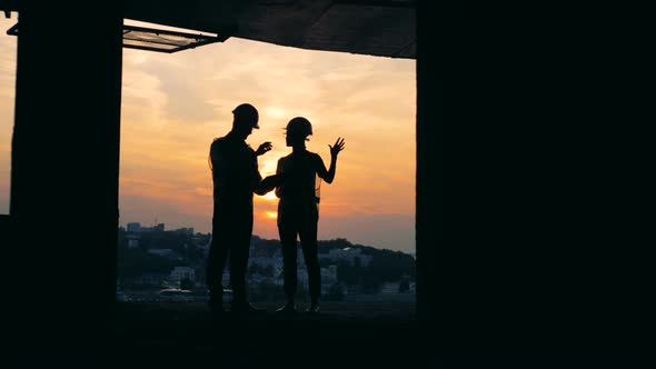 Architects Standing in Unfinished Building on a Sunset Background alt