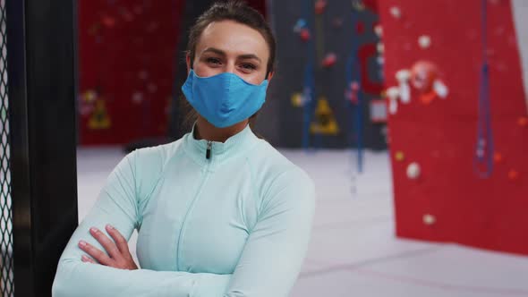 Portrait of smiling caucasian woman wearing face mask at an indoor climbing gym