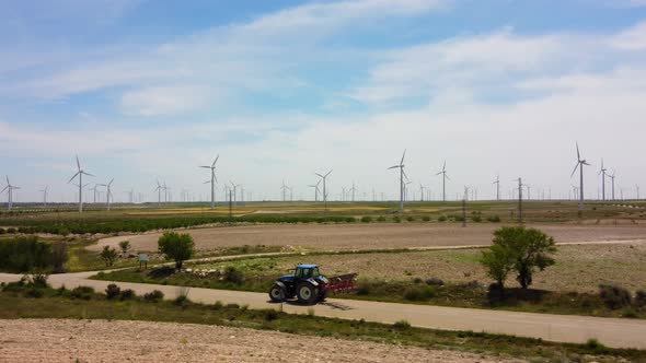 Tractor Driving On The Road With Windmills In The Background