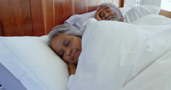 Side view of mixed race senior couple sleeping in bedroom at home 4k