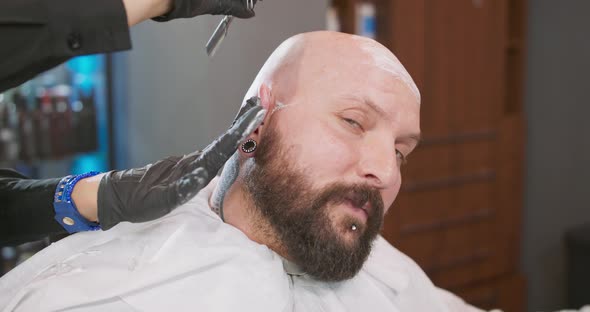 Closeup Head of Young Bearded Man Who is Sitting on the Barber's Chair Facing the Mirror and Hands