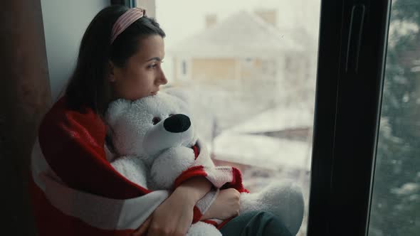 Woman Sitting with Teddy Bear on Windowsill