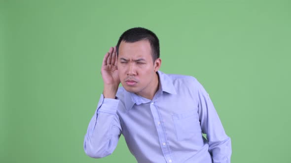 Stressed Asian Businessman Listening and Looking Shocked