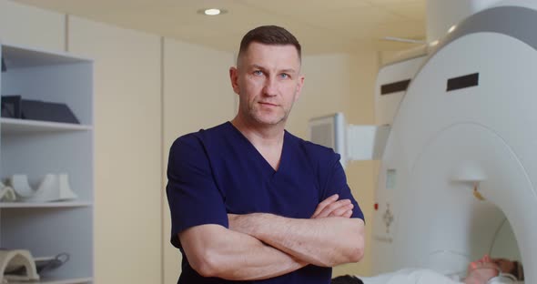 A Doctor Looks Into the Camera Standing in Front of an MRI Machine