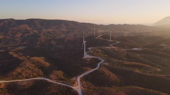 Windmills farm for power production on beautiful landscape at sunrise