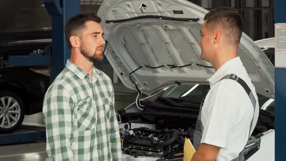 Cheerful Man Shaking Hands with Car Mechanic at Service Shop