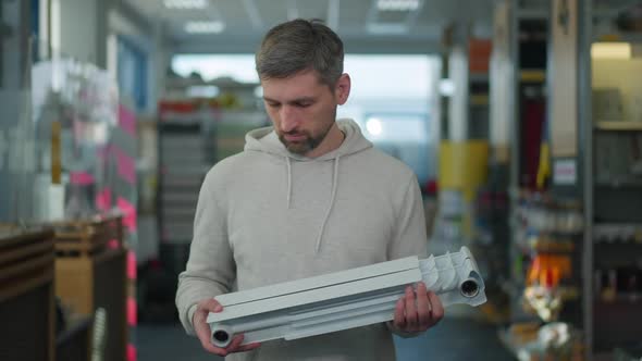 Satisfied Client Holding Radiator Section in Hardware Store Looking at Camera and Smiling